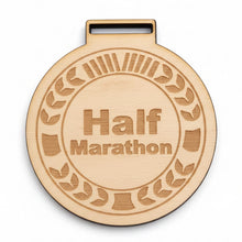 Load image into Gallery viewer, A wooden half marathon medal lying on grass, with an engraved text that reads 'Half Marathon'.

